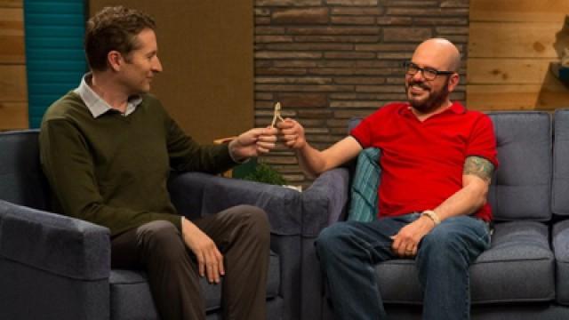 David Cross Wears A Red Polo Shirt & Brown Shoes With Red Laces