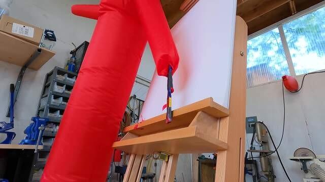 Taping a paint brush to an inflatable tube guy