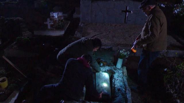 Tres hombres junto a una tumba abierta